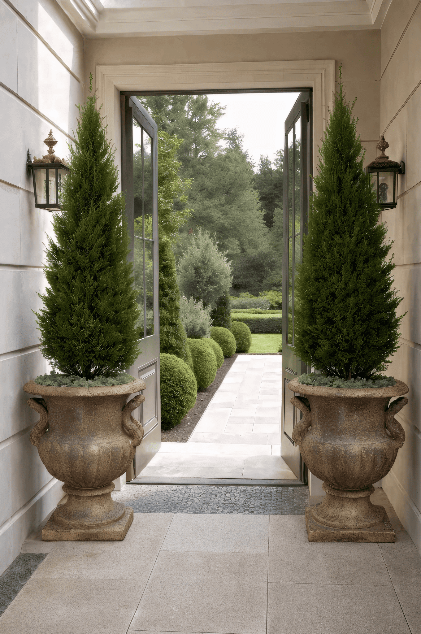 Two large ceramic planters with tall tropical plants decorating the garden entrance of a Mediterranean style house