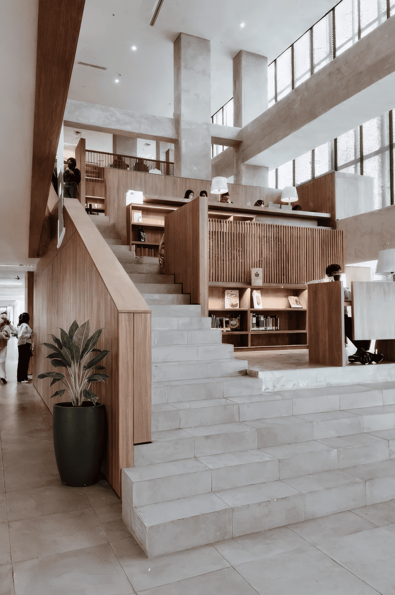 Large floor planter with indoor plant placed beside the staircase inside a contemporary university library interior