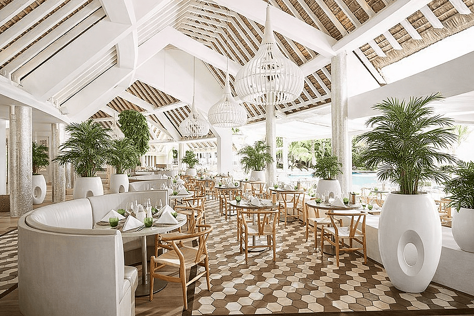 Large modern fiberglass planters with palm plants placed inside a bright open air resort restaurant