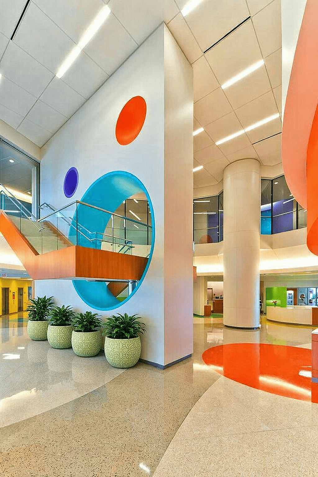 Round decorative planters with indoor plants placed in a bright modern school lobby interior